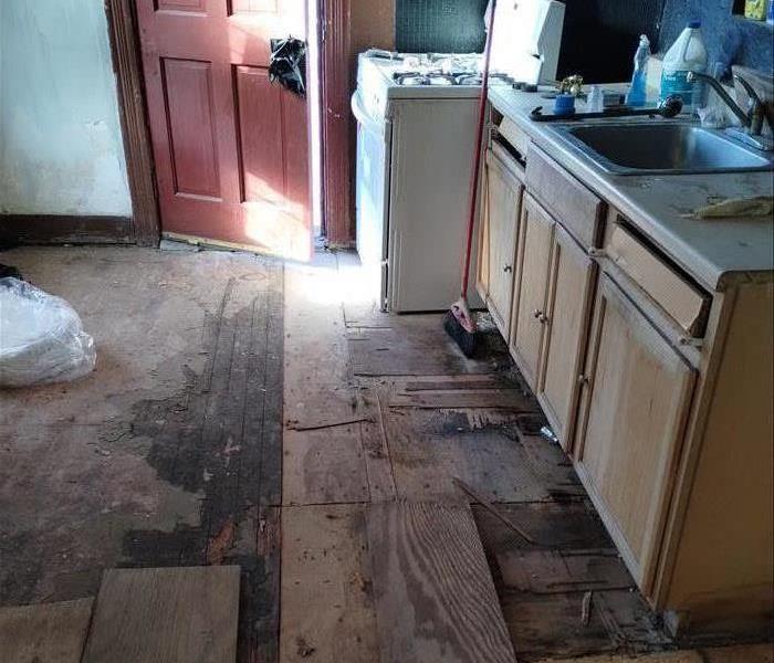 A flooded kitchen with ruined floors and cabinets.