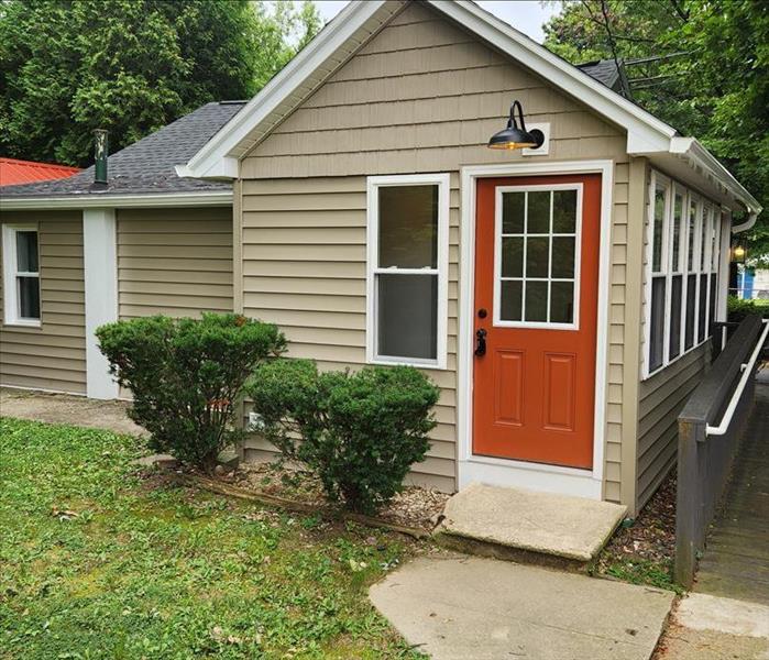 A newly renovated home is shown with beige siding and a new light fixture.