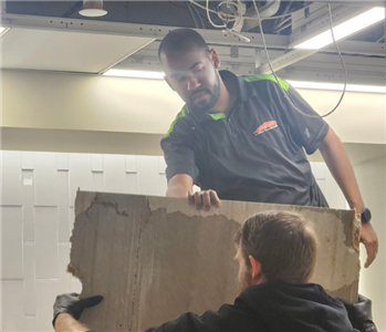 A SERVPRO employee hard at work taking down a ceiling.