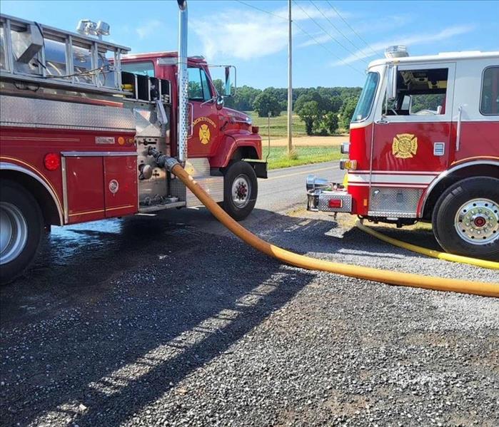 Two red fire trucks are shown on a paved street.